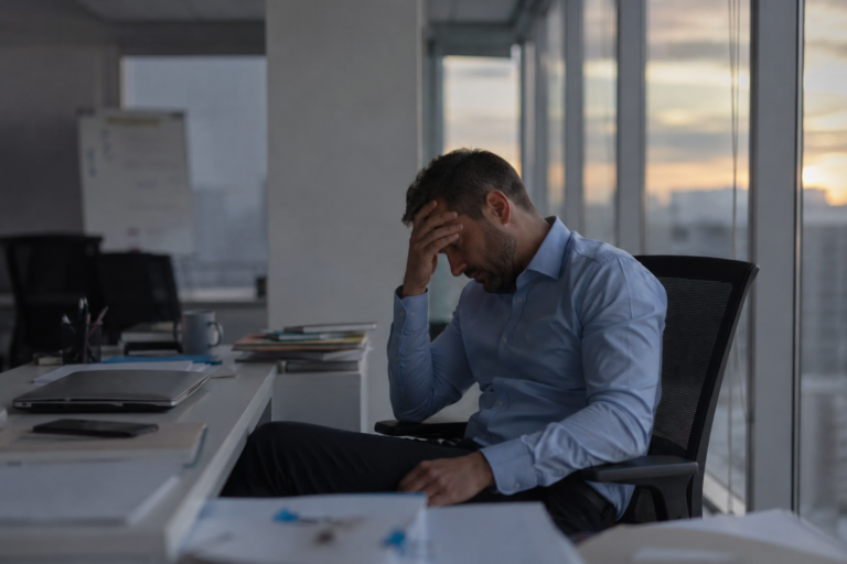 Homme assis dans un bureau ressentant les effets du stress chronique et de la fatigue mentale avant de découvrir les bienfaits du Tai Chi pour réduire le stress.
